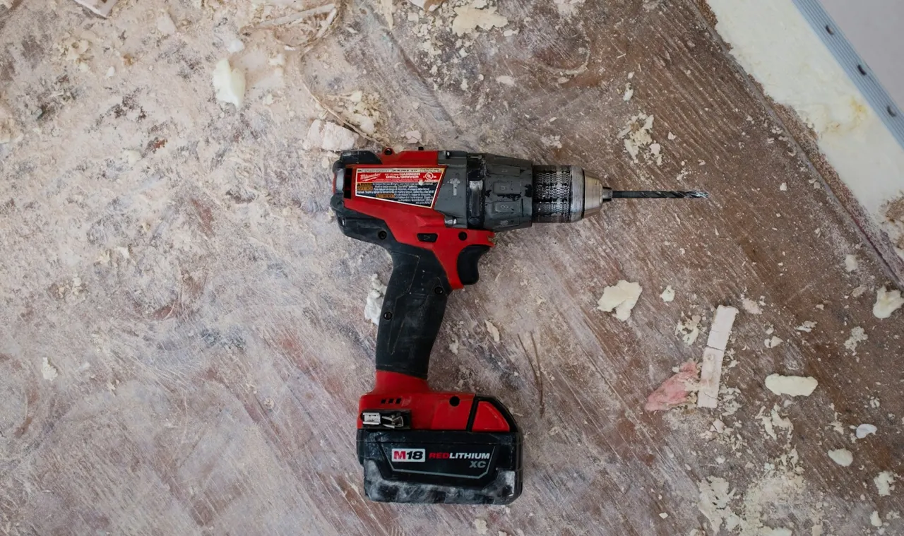 A power drill on a dusty work surface